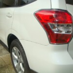 Before and after photographs of a damaged white Subaru that was repaired by Elite Paint & Body Shop in West Palm Beach, Florida